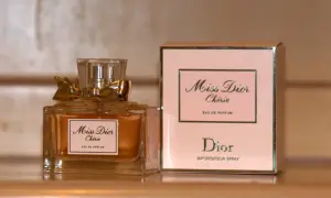 Elegancka butelka i pudełko perfum Miss Dior Chérie, ozdobione złotą kokardką, emanują luksusem.