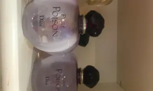 Dwa flakony perfum Pure Poison Dior 100ml, każdy z fioletową poświatą i czarnym korkiem.